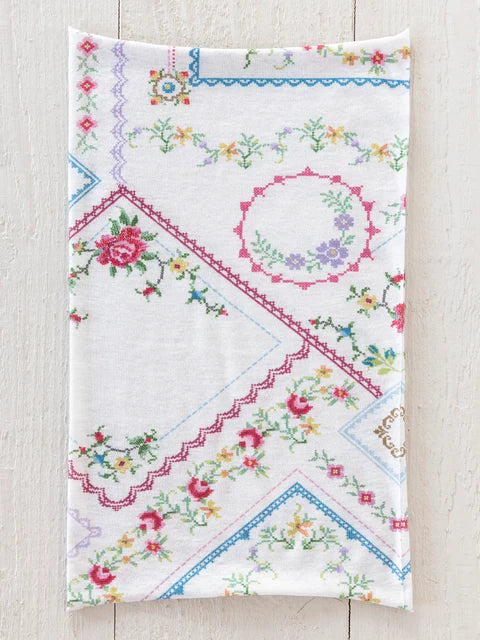 Embroidered fabric with floral and geometric patterns on a wooden surface