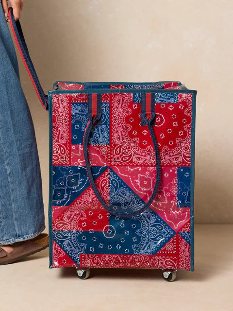 Red and blue patterned rolling shopping bag on a beige background