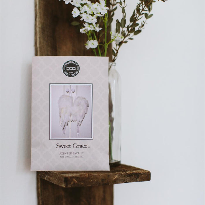 Wooden shelf with a vase of white flowers and a book titled 'Sweet Grace' on a white background