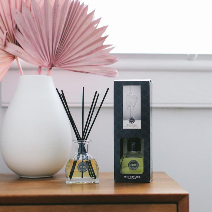 Diffuser with packaging on a wooden surface with a decorative plant in the background