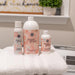 Bottles of 'sweet grace' products on a stack of white towels with a laundry room background.