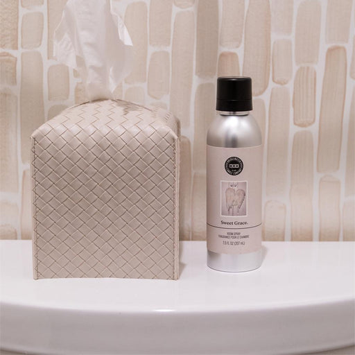 Bottle of cleaning spray and tissue box on a bathroom counter with tiled wall background
