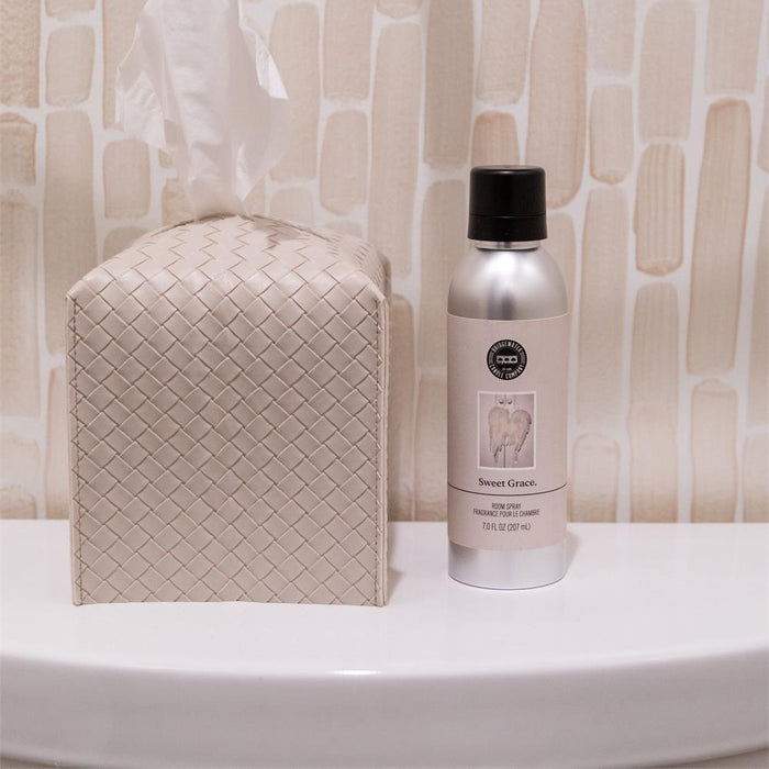 Bottle of cleaning spray and tissue box on a bathroom counter with tiled wall background