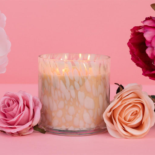 Candle with flowers on a pink background