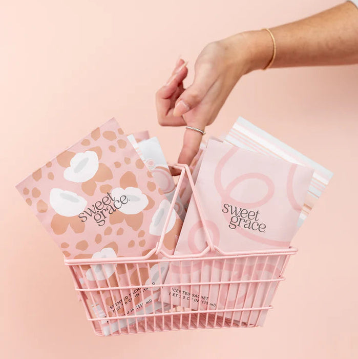 Hand reaching for a 'sweet grace' product in a basket on a pink background