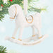 White rocking horse ornament with gold accents, '2026' and 'BABY'S 1ST CHRISTMAS' text, on a Christmas tree.