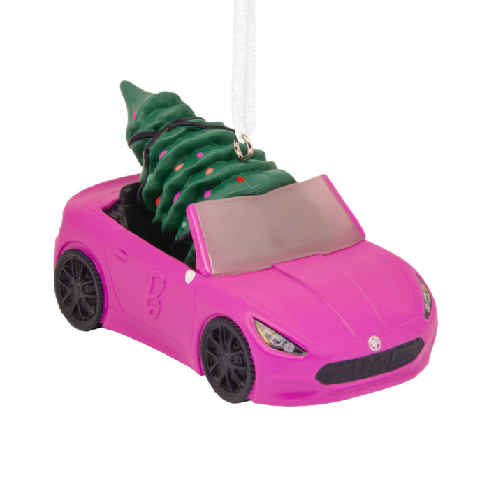A pink convertible car Christmas ornament with a green Christmas tree inside, hanging from a white ribbon on a white background.