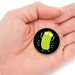 Hand holding a pickle-shaped pin with a black background