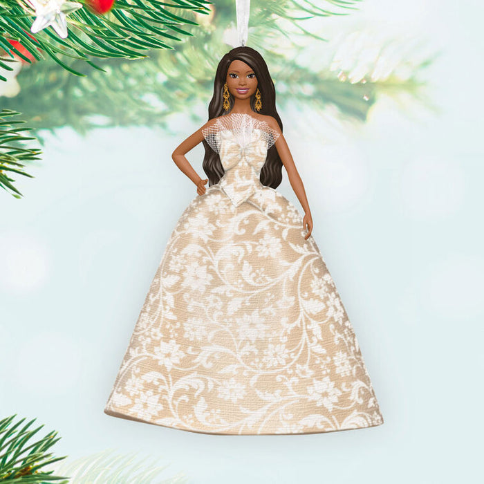 Barbie doll in a beige and white patterned dress with Christmas tree branches in the background