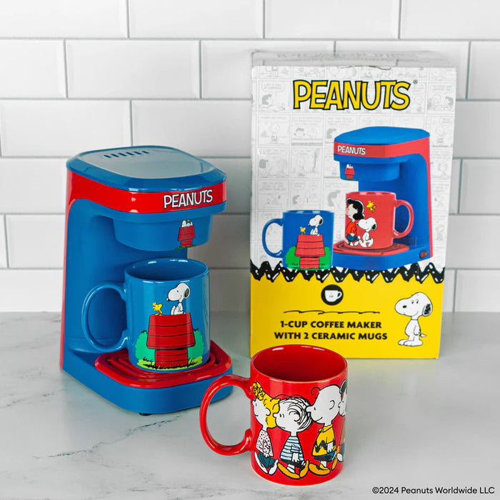 Peanuts-themed coffee maker with two mugs on a tiled wall background