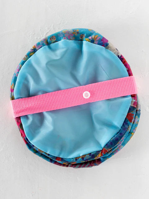 Blue drawstring bag with floral pattern and pink strap on a white background