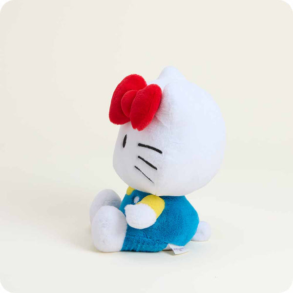 Plush toy resembling a character with a red bow and blue outfit on a light beige background