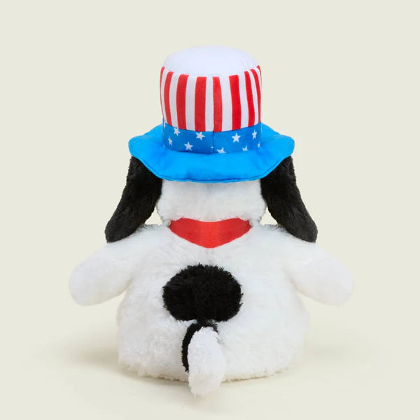 Stuffed dog toy with an American flag hat on a beige background
