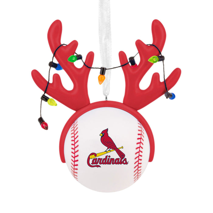 A Cardinals baseball ornament with red antlers, hanging white ribbon, and multicolor Christmas lights on a white background.