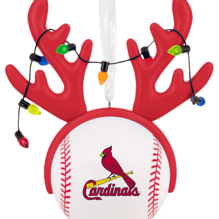 A Christmas ornament shaped like a baseball with red antlers on top, decorated with multicolored string lights, and featuring the St. Louis Cardinals logo on the front.