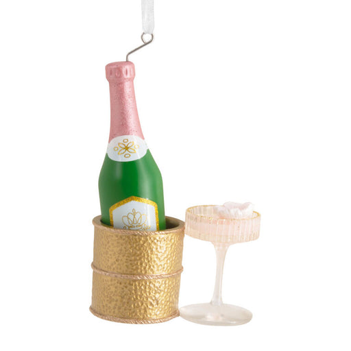 Decorative ornament of a champagne bottle in a gold cooler with a glass on a white background