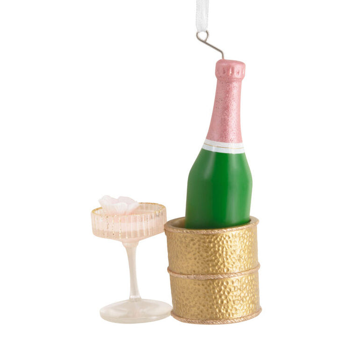 Decorative ornament resembling a champagne bottle in a gold bucket with a small glass on a white background