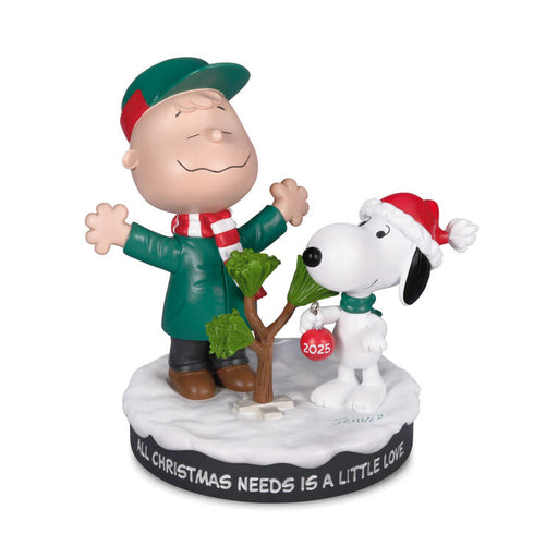 Figurine of Charlie Brown and Snoopy with a tree, wearing Christmas hats and scarves, on a white background.