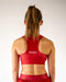 Person wearing a red sports bra with 'CHICKENLESS' branding on a plain background