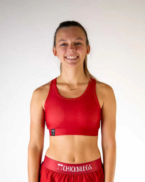 Person wearing a red sports bra and shorts with 'Chicken Legs' branding on a white background