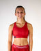 Person wearing a red sports bra and shorts with 'Chicken Legs' branding on a white background