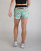 Person wearing a patterned teal shorts on a plain background