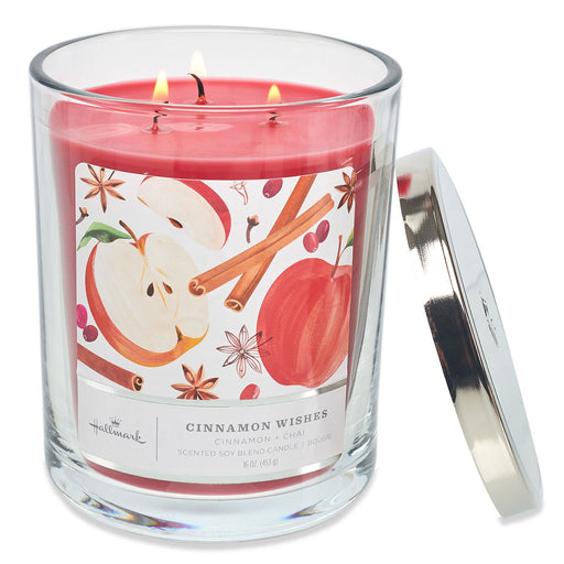 Candle with a cinnamon and apple design on the label, featuring two lit wicks.