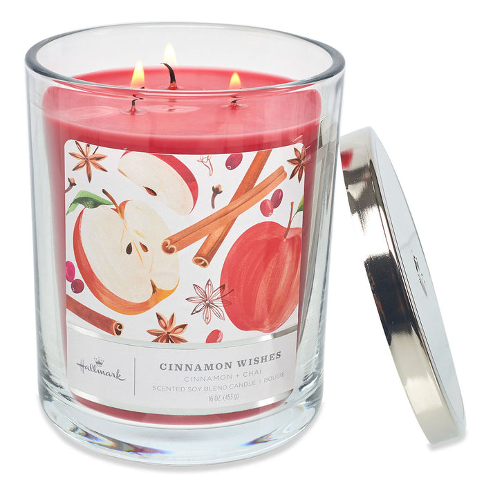 Candle with a cinnamon and apple design on the label, featuring two lit wicks.
