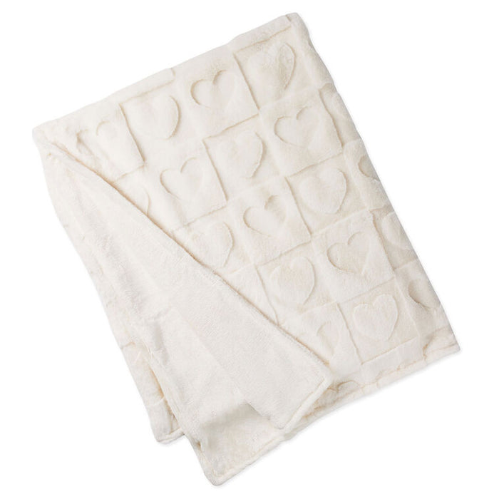 Folded cream-colored blanket with heart patterns on a white background