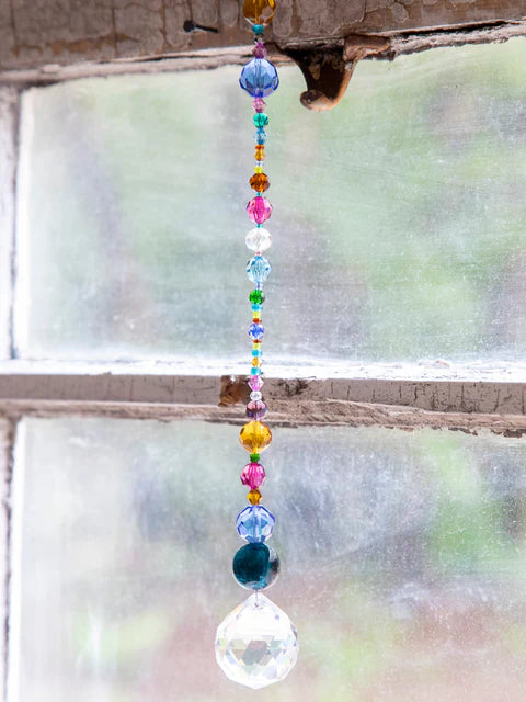 Colorful beaded hanging ornament in front of a window