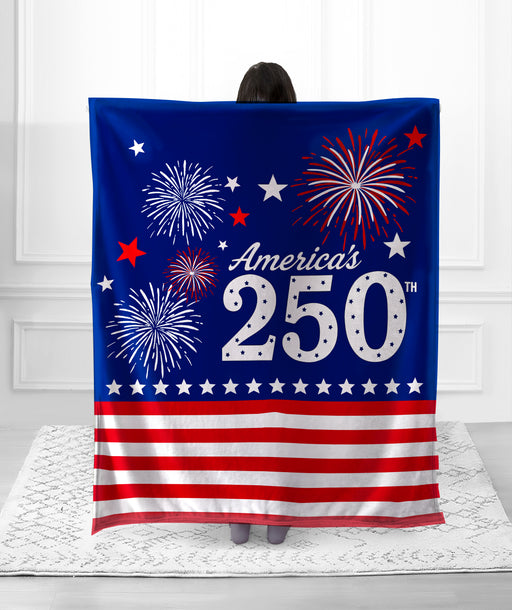Person holding a decorative blanket with American flag and fireworks design.