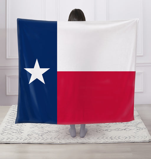 Person holding a Texas flag blanket in a room with white walls and a light-colored rug.