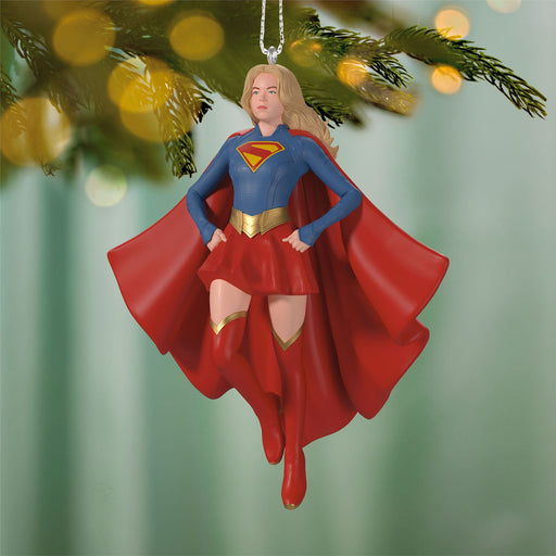 Superman character ornament hanging on a Christmas tree with blurred lights in the background