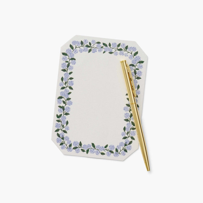 Notebook with floral design and gold pen on a white background