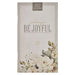A vertical daily planner with a textured cream cover, featuring the words 'always BE JOYFUL' in elegant typography, a '2027 DAILY PLANNER' label at the top, and a floral illustration in soft cream, white, and muted green tones near the bottom.