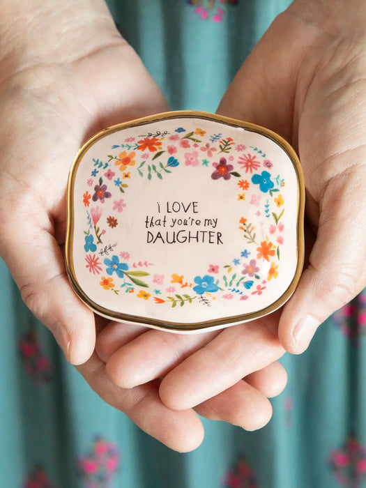 Holding a decorative compact mirror with floral design and text.
