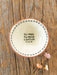Decorative plate with 'You make the world a better place' text on a wooden surface with flowers.