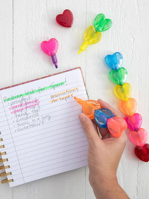 Colorful heart-shaped highlighters on a notebook with a hand holding one.