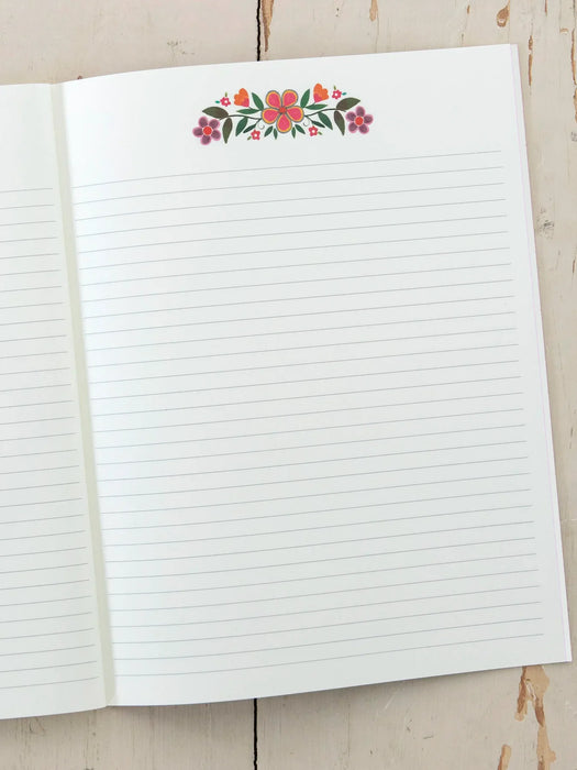 Open notebook with lined pages and floral design on a wooden surface
