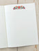Open notebook with lined pages and floral design on a wooden surface