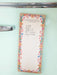 A vertical notepad with a floral border and handwritten text reading 'with egg yogurt ice cream dig treats' is photographed hanging on a mint green refrigerator door next to a chrome handle.