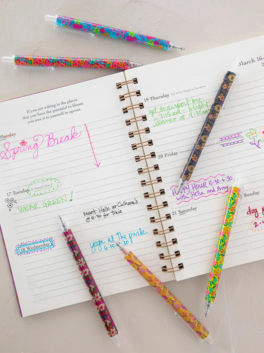 Open notebook with handwritten notes and colorful pens on a light surface