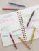Open notebook with handwritten notes and colorful pens on a light surface
