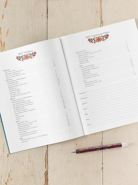 Open planner with floral designs on a wooden surface