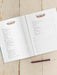 Open planner with floral designs on a wooden surface