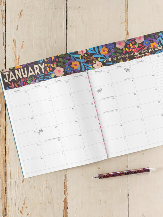 Calendar open to January with colorful floral design on a wooden surface