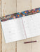 Calendar open to January with colorful floral design on a wooden surface