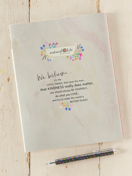 Notebook with motivational quote and floral design on a wooden surface