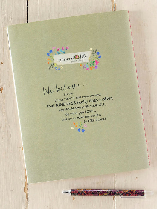 Green notebook with inspirational quote and pen on a wooden surface, featuring 'natural life' branding.