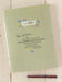 Green notebook with inspirational quote and pen on a wooden surface, featuring 'natural life' branding.